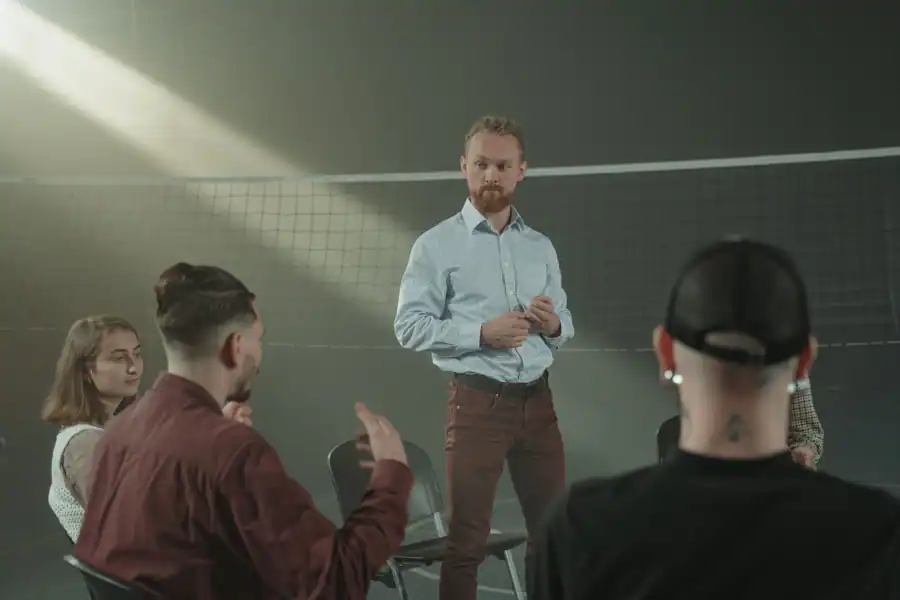 Four people engaged in a group discussion inside a room with a net background.